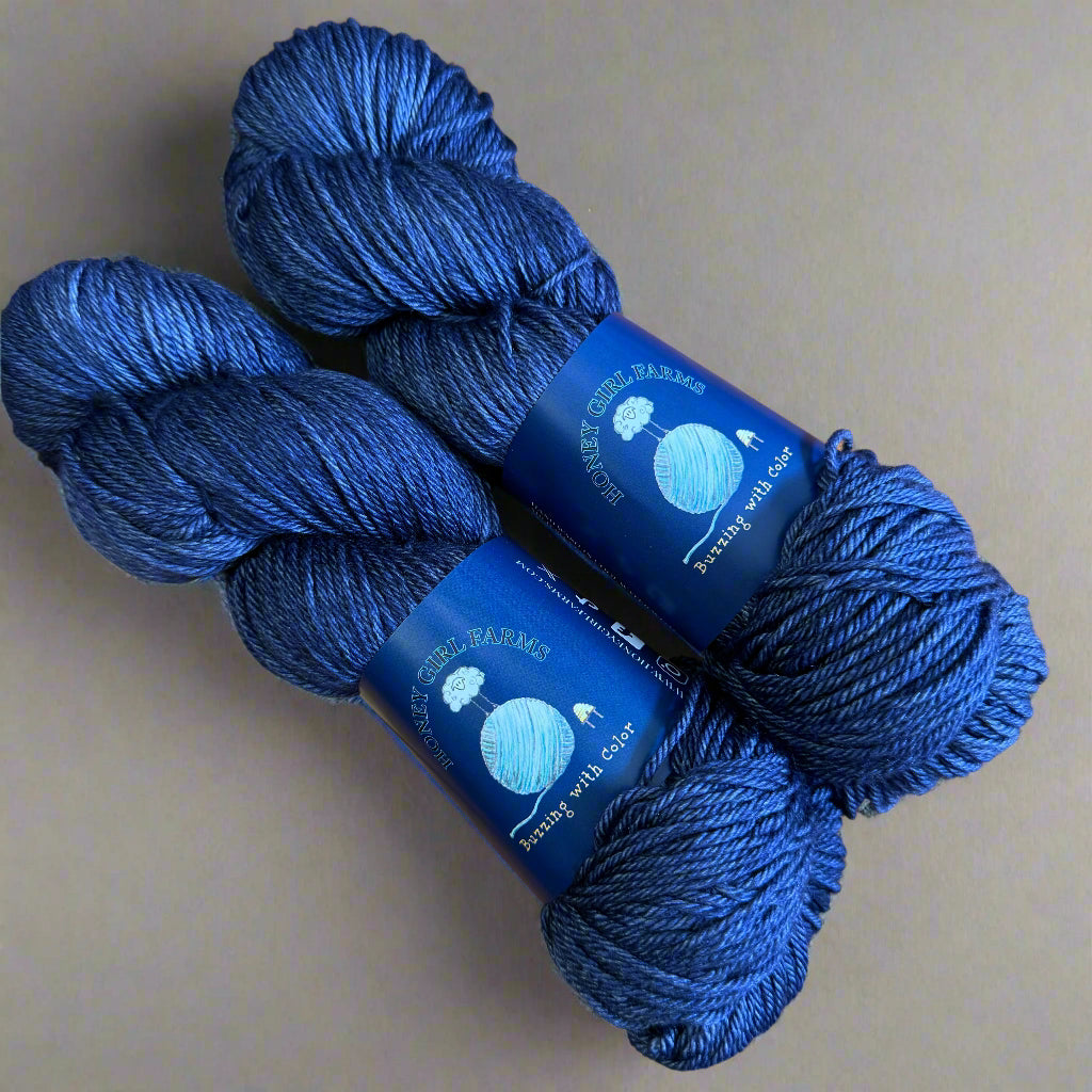 Two skeins of blue yarn with labels on a gray surface