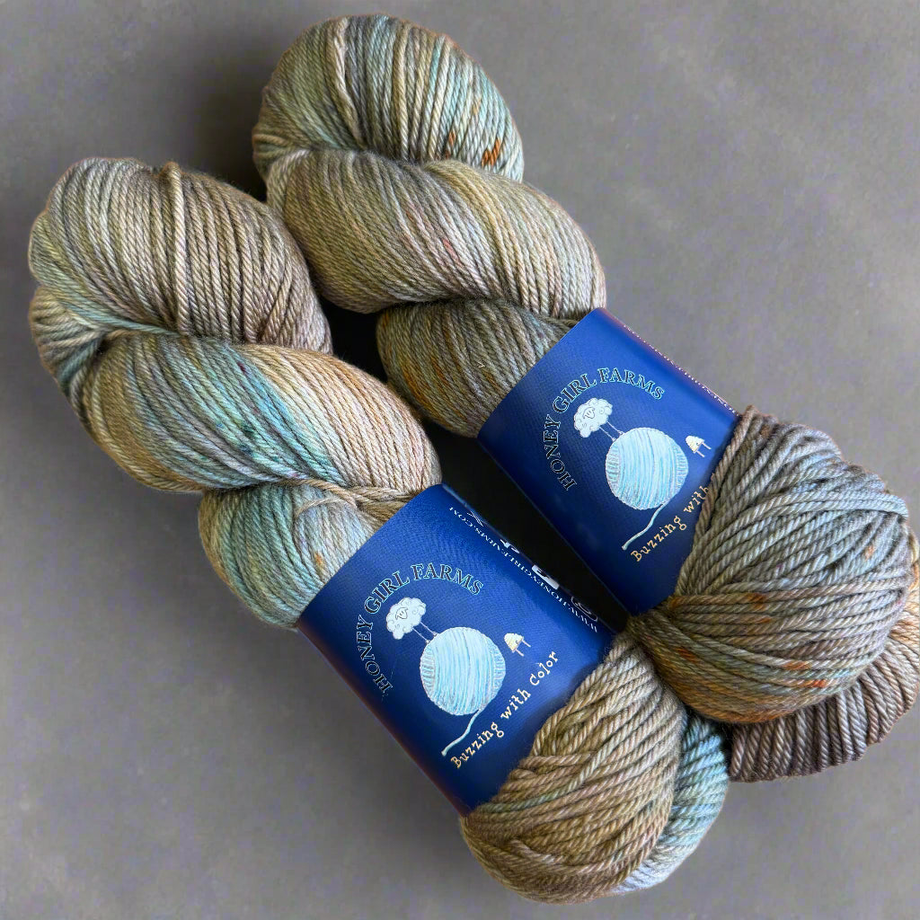Two skeins of yarn with blue labels on a gray surface