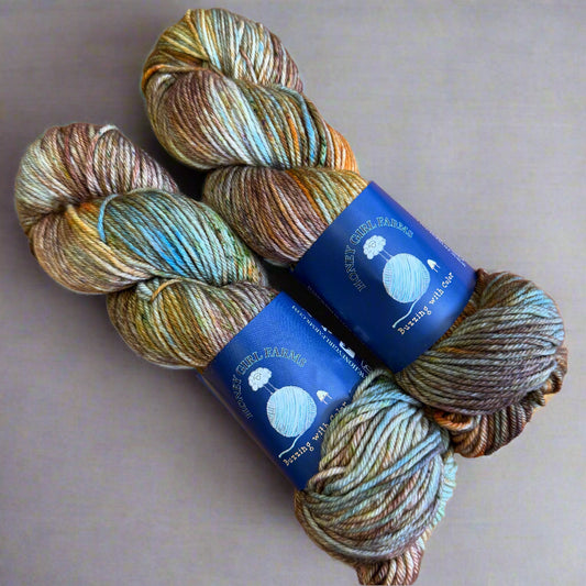 Three skeins of multicolored yarn with blue labels on a gray surface