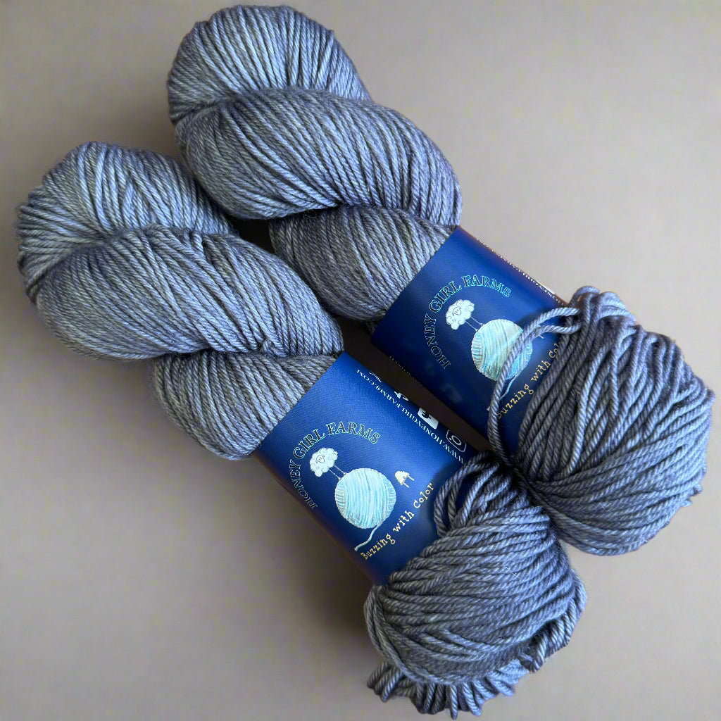 Three skeins of gray yarn with blue labels on a gray surface