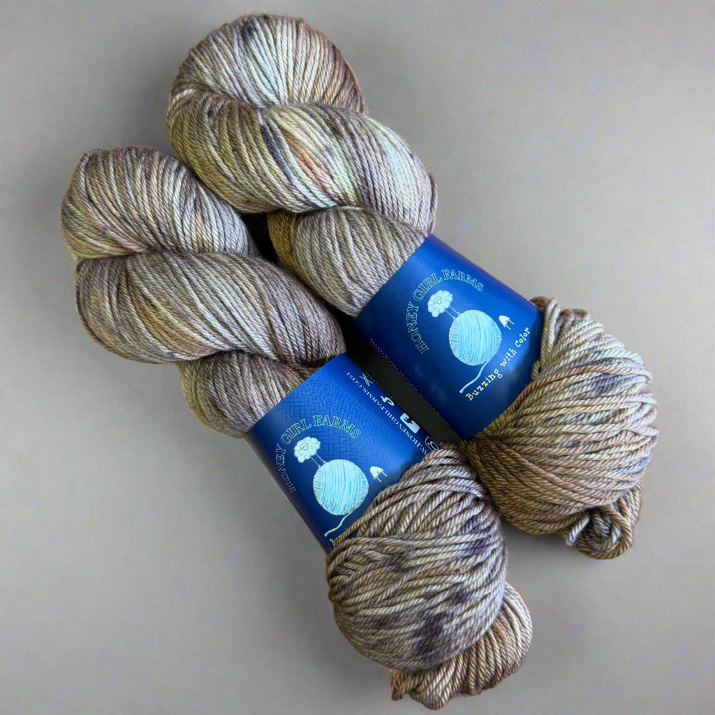 Three skeins of yarn with blue labels on a gray surface